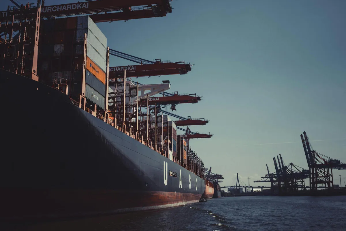 Container vessel at port terminal with loading cranes — maritime delivery logistics