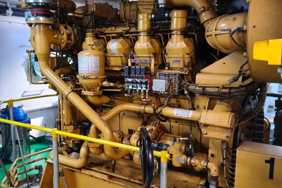 Caterpillar marine auxiliary engine installed in a ship engine room, showing cylinder head covers, oil filter housing, turbocharger and engine-mounted wiring