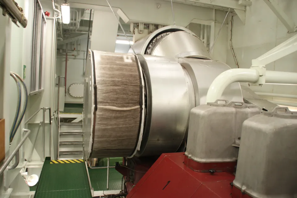 Main engine exhaust gas turbocharger in a ship engine room with its intake filter silencer and the scavenge air receiver behind
